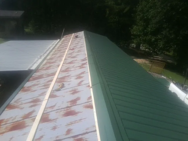 Old rusted panels beside newly installed green metal roofing — Wind Damage Roof Repair by Roofing Brothers in Orange